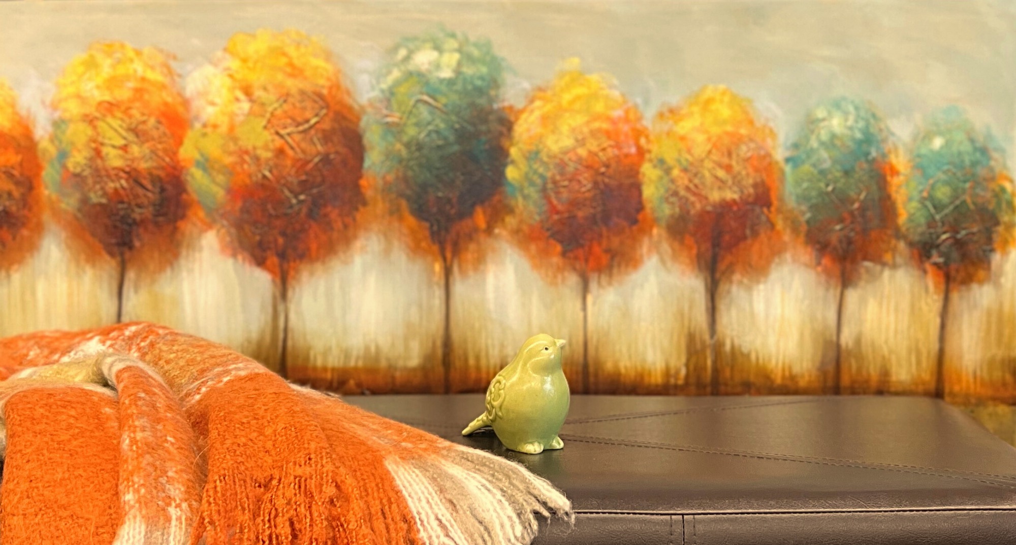 Canvas with fall trees, orange plaid throw blanket, bench, and bird