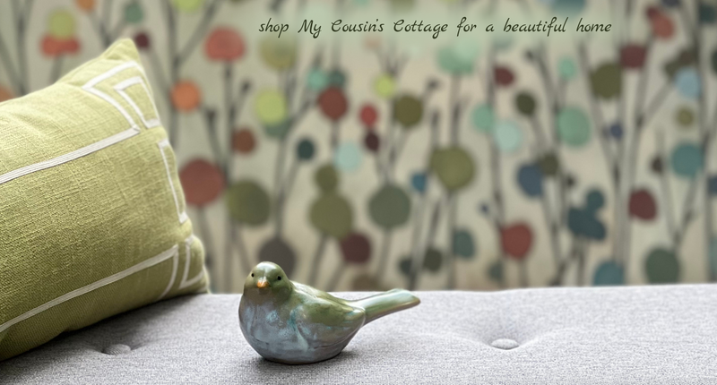 Ceramic bird, green pillow, gray bench and floral canvas